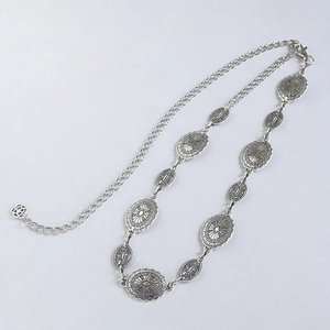 Macro shot of silver bohemian waist chain with vintage embossed floral metal plates
