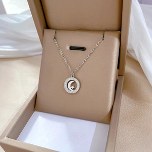 Close-up of star and moon pendant necklace with crystals in a beige jewelry box