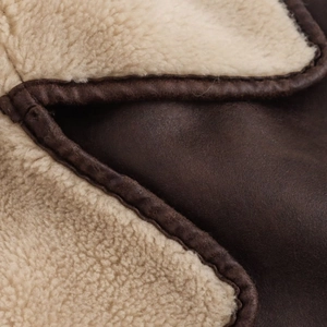Close-up of brown faux leather jacket with white shearling lining and premium stitching