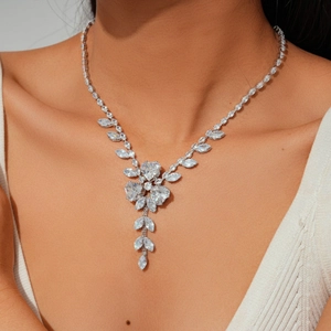 Detail of silver floral necklace with marquise zircons and leaf tassel design on model
