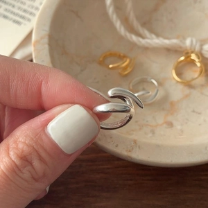 Close-up of minimalist gold and silver overlapping geometric rings on a model hand