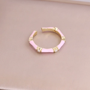 Detailed macro view of pink enamel bamboo ring with gold accents and sparkling stones