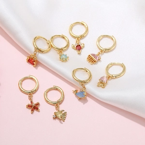 Close-up of 18K gold hoop earrings with colorful marine animal charms on silk fabric