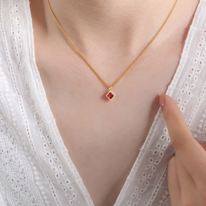 Elegant gold chain necklace featuring a square red zircon pendant on a white lace outfit