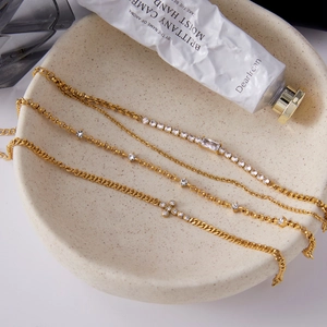 Détail d'un ensemble de quatre bracelets dorés avec croix en zircon et chaîne tennis