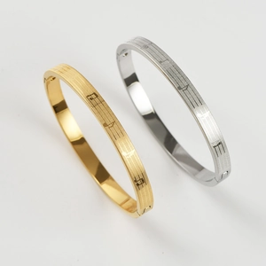 Detail shot of gold and silver titanium steel bracelets with engraved musical notes