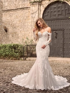 Detail of elegant floral lace sleeves and mermaid silhouette on white bridal gown