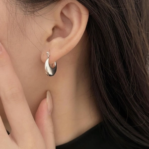 Detailed close-up of polished S925 sterling silver U-shaped hoop earrings on model ear