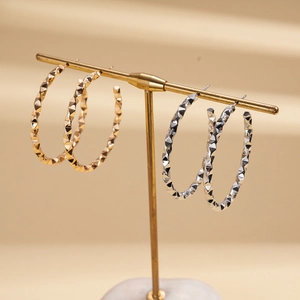 Geometric C-shaped hoop earrings in gold and silver with diamond-cut metal texture