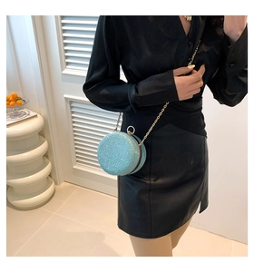 Detail of light blue sequined round evening bag with gold chain strap on black outfit
