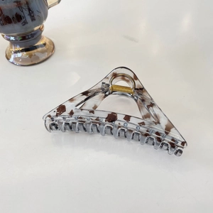 Detailed view of triangular tortoiseshell hair claw clip with golden metal spring