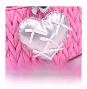 Close-up of pink quilted fabric with a silver heart and white bow embellishments