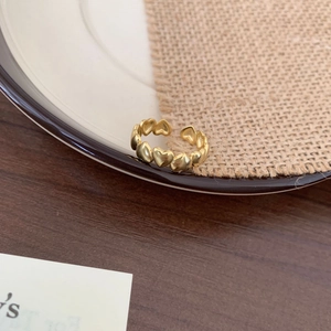 Detailed view of connected golden heart-shaped patterns on polished adjustable open ring