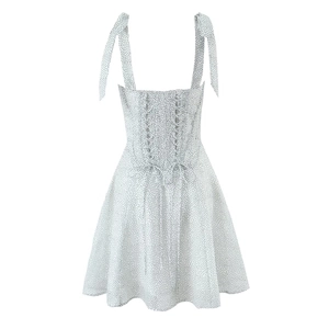 Detail of adjustable tie-shoulder straps and lace-up back on a white polka dot mini dress