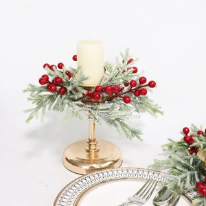 Close-up of golden candle holder with green pine needles, red berries and frosted finish