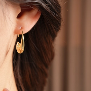 Close-up of elegant 14k gold plated drop earrings on model with a glossy metallic finish