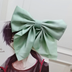 Macro detail of a large mint green matte fabric bow hair clip on a decorative card