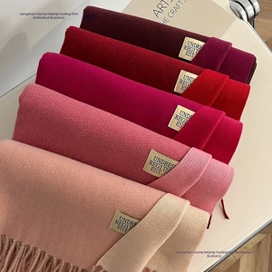 Detailed view of winter cashmere-like scarves showing fringe and gold logo accents