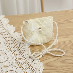Detail of cream straw bag with mesh bow, pearl accent and woven rope strap on lace
