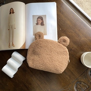 Brown teddy fleece bear shaped shell makeup bag with cute ears on a wooden desk
