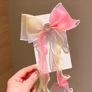 Detailed view of children's gradient pink-yellow chiffon bow hairclip with sparkling rhinestones
