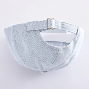 Detail of adjustable metal buckle and light blue denim texture on child baseball cap