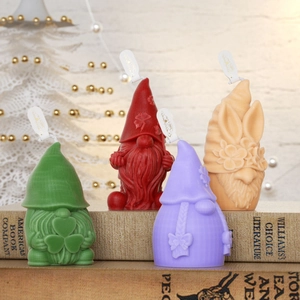 Set de cuatro velas de gnomos de colores en verde, rojo, lila y naranja sobre libros
