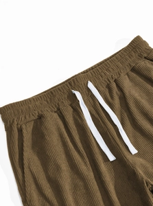 Detail of corduroy fabric texture with adjustable drawstring and elastic waistband on brown pants