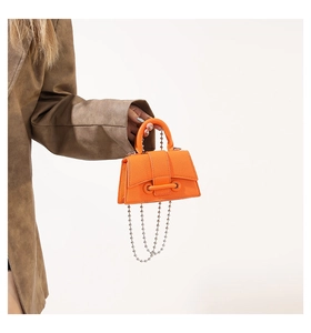 Detail of orange lychee leather mini handbag with long silver beaded chain accessory