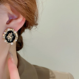 Detail of vintage round earring with black enamel cameo and elegant pearls