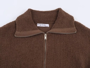 Macro detail of dark brown teddy fleece bomber jacket with silver zipper and neck label