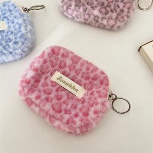 Dettaglio di pochette in peluche leopardate con chiusura a zip e anelli in metallo
