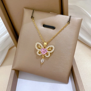 Macro shot of gold butterfly necklace with pink heart gem in a premium gift box