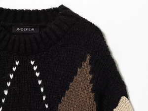 Detail of chunky knit sweater with argyle pattern and white heart stitch accents