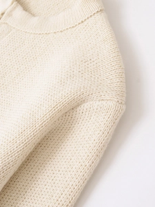 Dettaglio macro del maglione in maglia crema con scollatura a coste e trama spessa