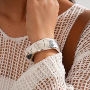 Close-up of a wide polished silver resin bangle worn by a model with casual style