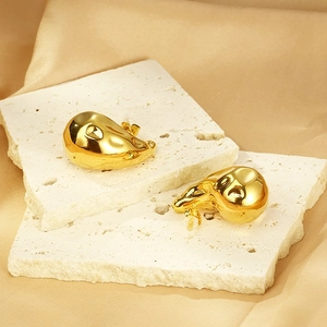 Vue détaillée de boucles d'oreilles gouttes dorées 18K sur pierre et soie douce