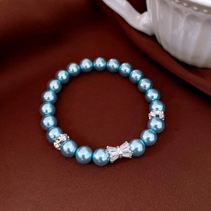 Détail du bracelet en perles bleues avec breloque nœud argenté et strass scintillants