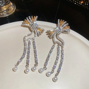 Detail of silver bow tassel earrings with sparkling cubic zirconia and white pearls
