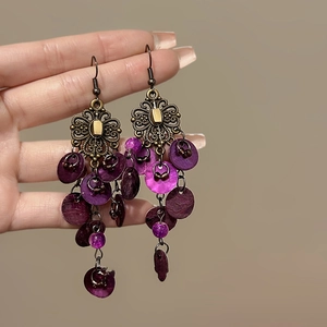 Close-up of vintage geometric shell fringe earrings with purple and bronze details