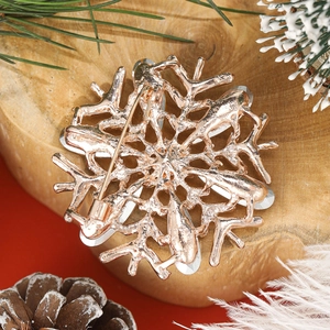 Macro detail of rose gold snowflake brooch showing pin structure and metal texture