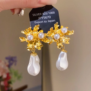 Detail of 925 silver needle floral pearl earrings with gold texture and baroque pendant