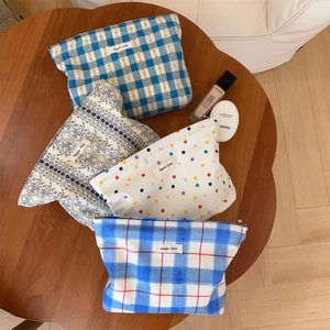 Detailed overhead view of four assorted cotton cosmetic bags with floral and plaid patterns