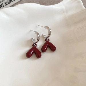 Silver-plated hoop earrings with glossy deep red heart pendant in a ceramic bowl