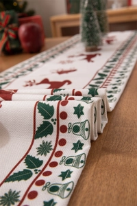Detail of Christmas table runner with red reindeer and green holly on woven fabric