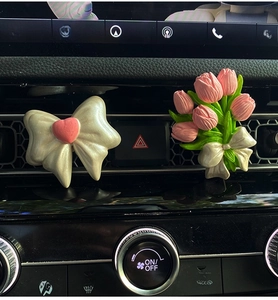 Detail of pink tulip and white bow car vent aromatherapy diffusers in auto interior
