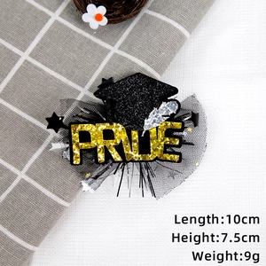 Detail view of mini graduation cap hair clip with black mesh and gold glitter letters