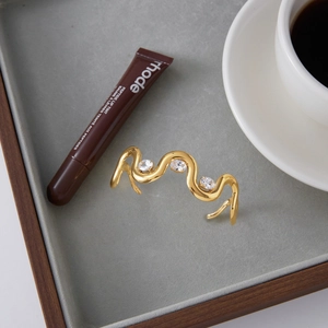 Detailed close-up of a gold wave-shaped bangle with three cubic zirconia stones on velvet