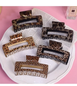 Detail showing five assorted leopard print rectangular hair claws on vintage paper