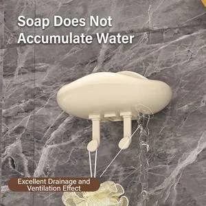 Cream cloud-shaped soap holder with drainage holes and hooks on a marble wall